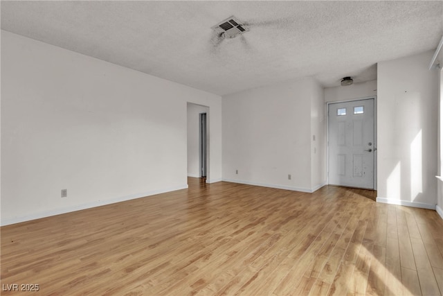 interior space with a textured ceiling, baseboards, visible vents, and light wood-style floors