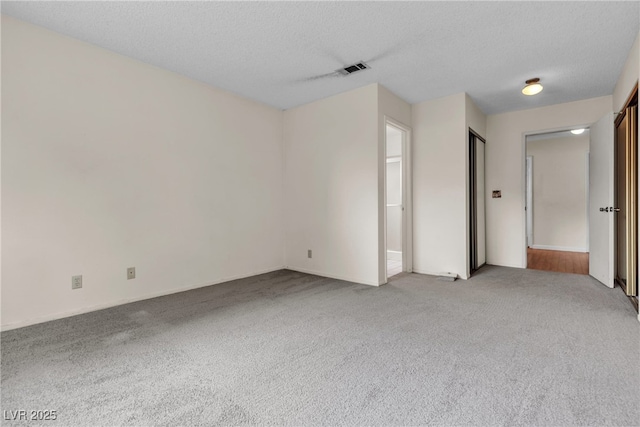 empty room featuring light carpet and a textured ceiling