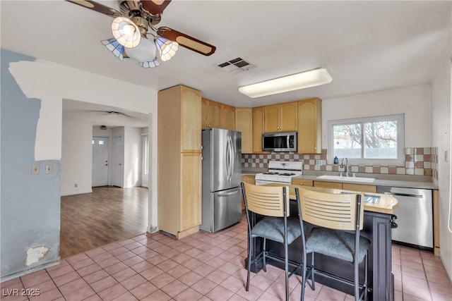 kitchen featuring stainless steel appliances, light countertops, visible vents, light brown cabinetry, and a sink