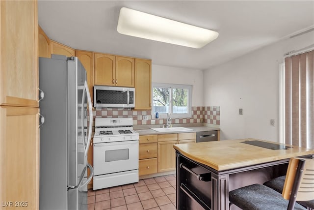 kitchen featuring appliances with stainless steel finishes, tasteful backsplash, a sink, and light brown cabinetry