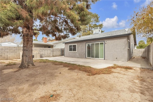 rear view of house featuring stucco siding, a fenced backyard, cooling unit, and a patio