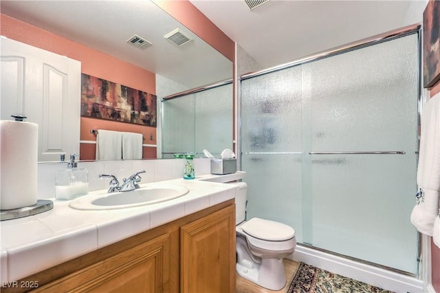 bathroom with visible vents, toilet, a shower stall, and vanity