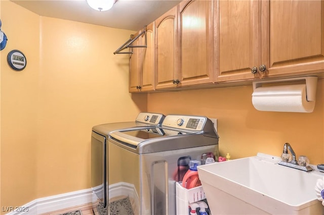 clothes washing area with cabinet space, a sink, and washer and clothes dryer