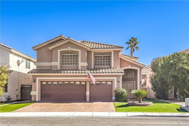 mediterranean / spanish home featuring a garage, a tile roof, decorative driveway, and stucco siding