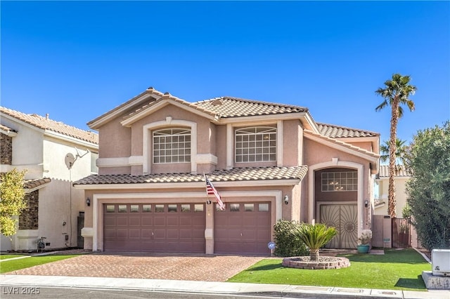 mediterranean / spanish home featuring a garage, a tile roof, decorative driveway, and stucco siding