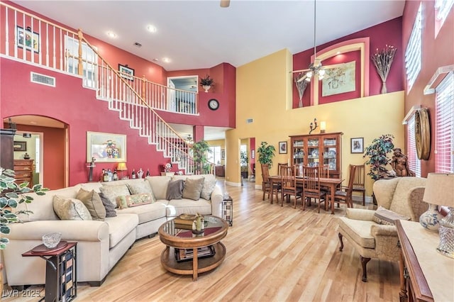 living room with stairs, arched walkways, visible vents, and wood finished floors