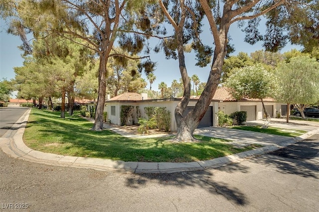 view of front of property featuring a tile roof, concrete driveway, a front yard, and stucco siding