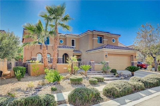 mediterranean / spanish-style house featuring fence, a tile roof, driveway, a gate, and stucco siding