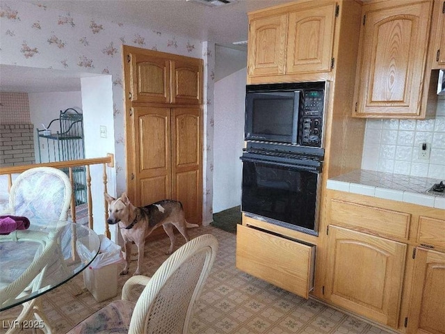 kitchen featuring decorative backsplash, tile counters, and black appliances