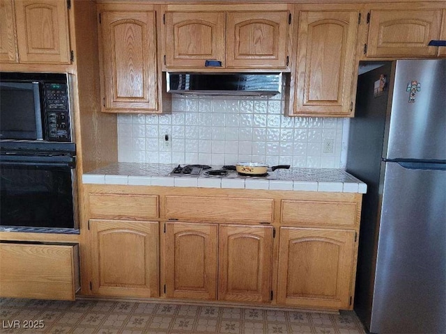 kitchen featuring ventilation hood, tasteful backsplash, tile counters, and black appliances