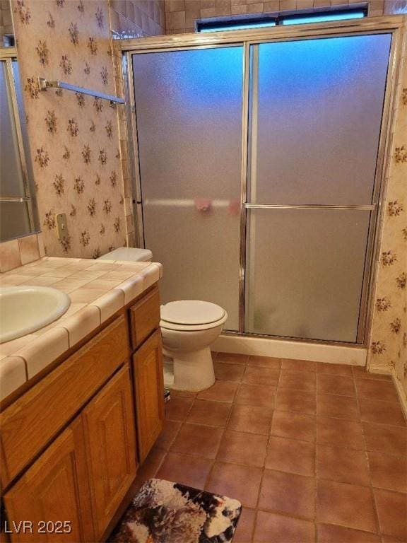 bathroom with vanity, tile patterned flooring, a shower with shower door, and toilet