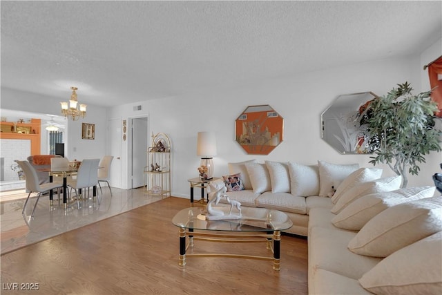 living room featuring a textured ceiling, a notable chandelier, and wood-type flooring