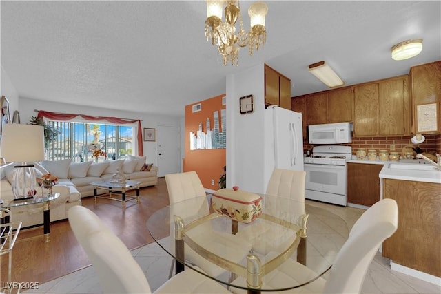 dining space featuring sink, a textured ceiling, and a notable chandelier