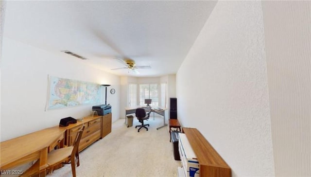 carpeted home office featuring ceiling fan