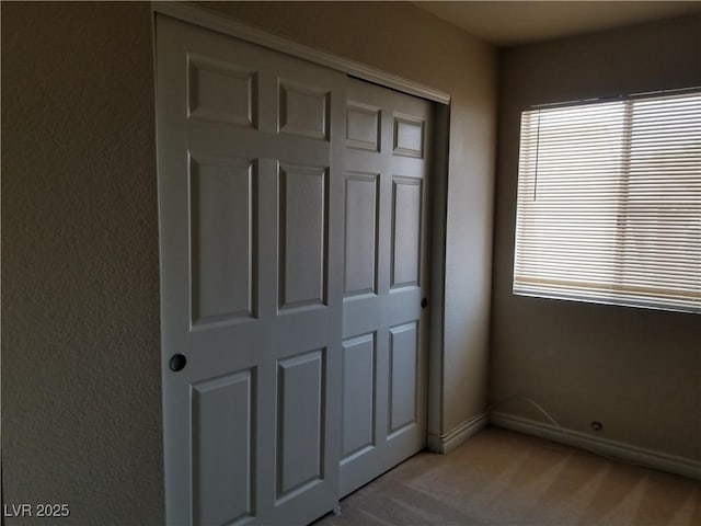 unfurnished bedroom with multiple windows, light colored carpet, and a closet