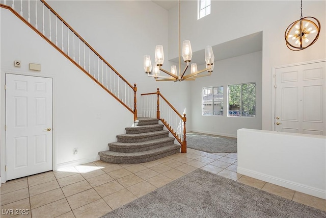 tiled entryway with plenty of natural light, a towering ceiling, and a chandelier