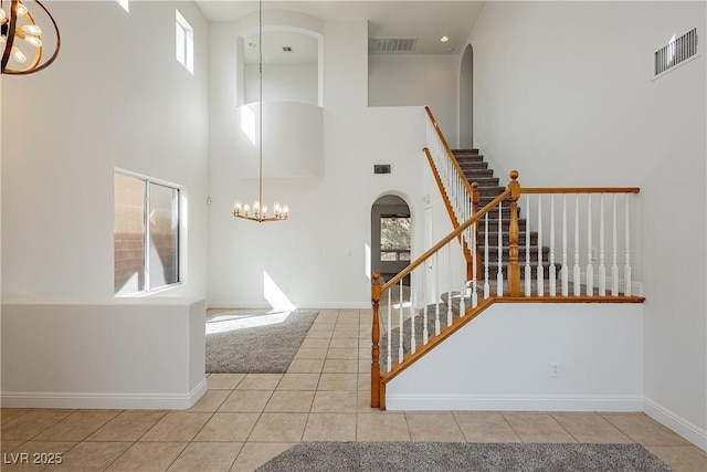 stairway featuring tile patterned floors, a high ceiling, and a notable chandelier