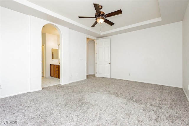 carpeted spare room featuring a tray ceiling and ceiling fan