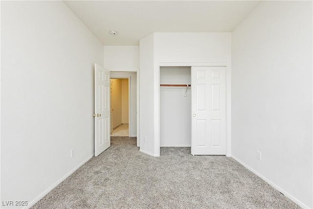 unfurnished bedroom featuring light carpet and a closet