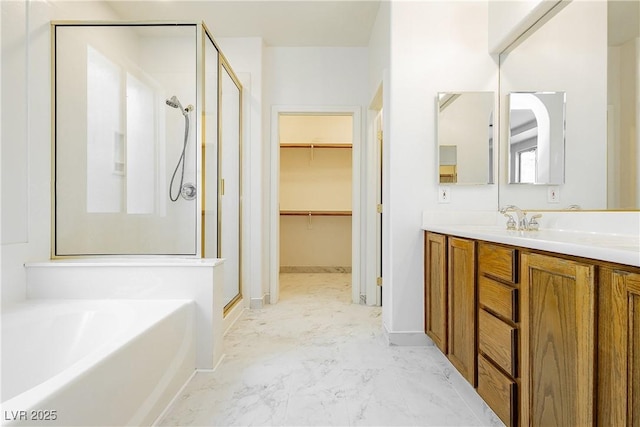 bathroom featuring a bath, a walk in closet, a shower stall, vanity, and marble finish floor