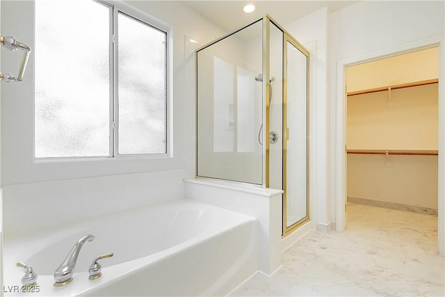 full bath featuring a spacious closet, a bath, a shower stall, and baseboards