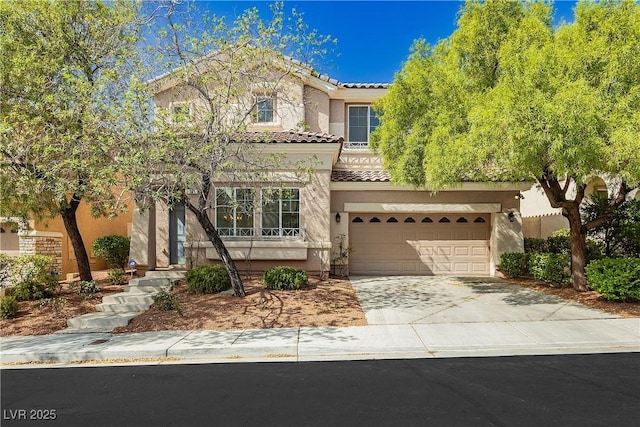 mediterranean / spanish home with a tiled roof, an attached garage, stucco siding, and concrete driveway
