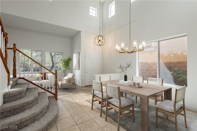 dining area featuring baseboards, an inviting chandelier, a high ceiling, light tile patterned flooring, and stairs
