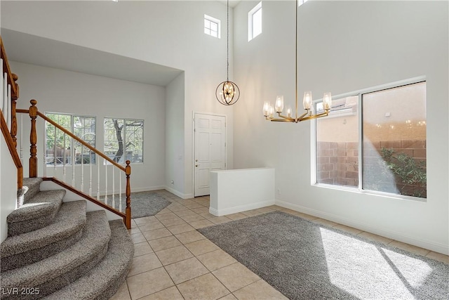 entrance foyer featuring baseboards, a chandelier, stairway, light tile patterned floors, and a high ceiling