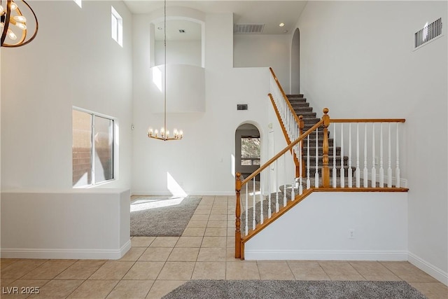 foyer entrance featuring visible vents, stairway, arched walkways, and an inviting chandelier