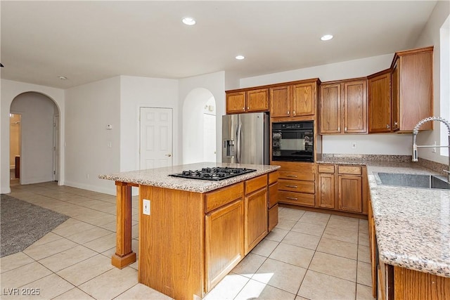 kitchen with arched walkways, a sink, black oven, and stainless steel fridge