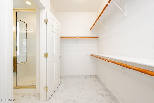 walk in closet featuring marble finish floor