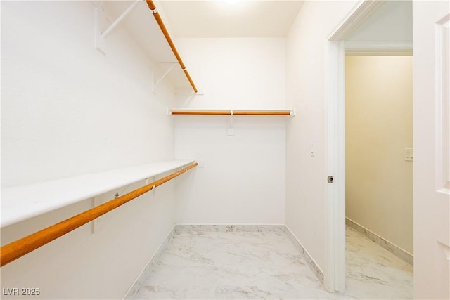 walk in closet featuring marble finish floor