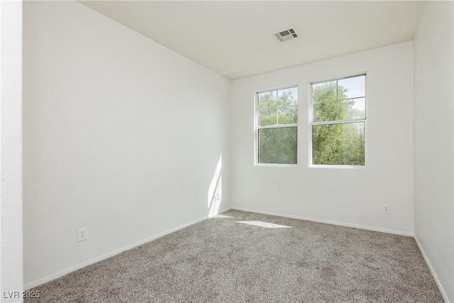 spare room with carpet flooring, baseboards, and visible vents