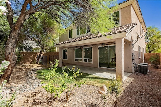rear view of property featuring central air condition unit, a tiled roof, stucco siding, and fence