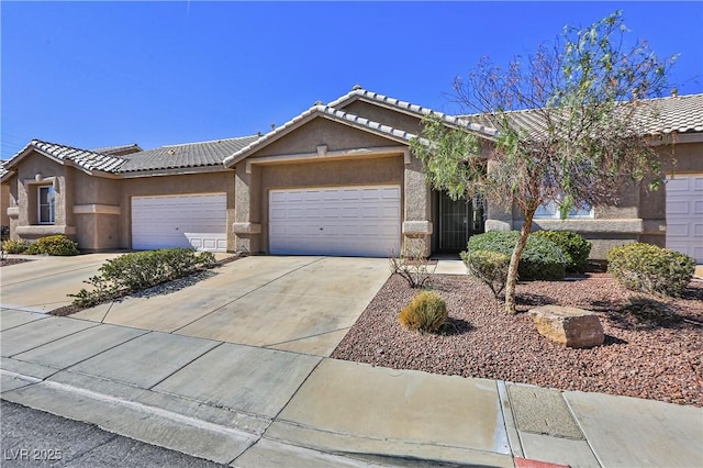 single story home with a garage, driveway, a tiled roof, and stucco siding