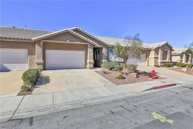 single story home with a garage, a tiled roof, concrete driveway, and stucco siding