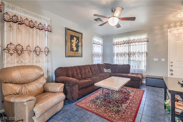 living room with ceiling fan, plenty of natural light, and dark tile patterned floors