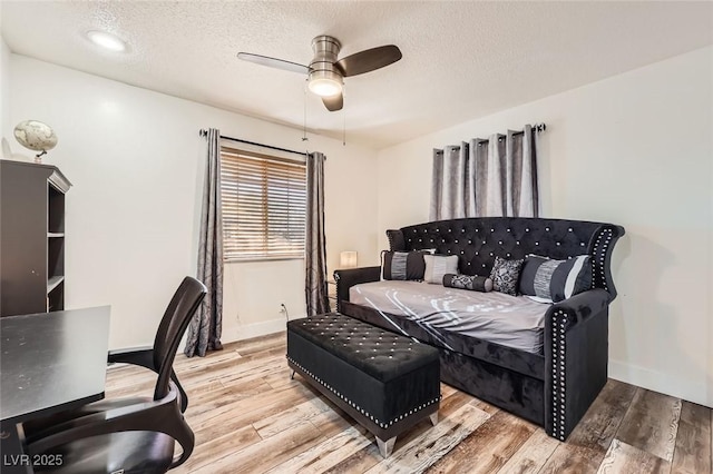 bedroom with a textured ceiling, light wood-style flooring, and baseboards