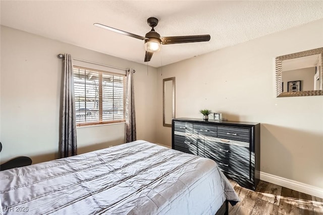 bedroom with a textured ceiling, ceiling fan, wood finished floors, and baseboards