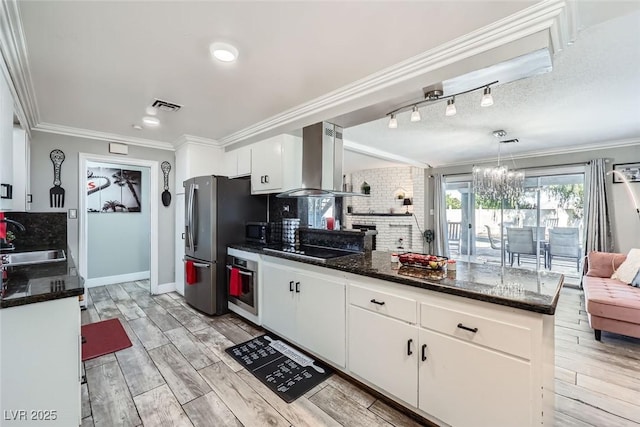 kitchen featuring decorative light fixtures, white cabinets, a sink, island range hood, and black appliances