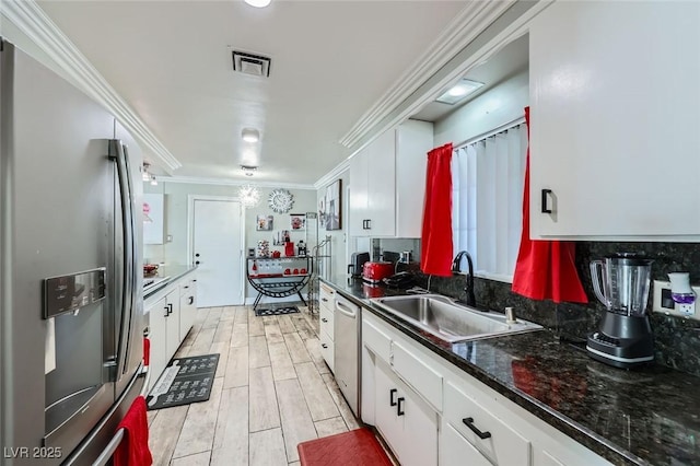 kitchen featuring stainless steel appliances, a sink, visible vents, white cabinets, and ornamental molding