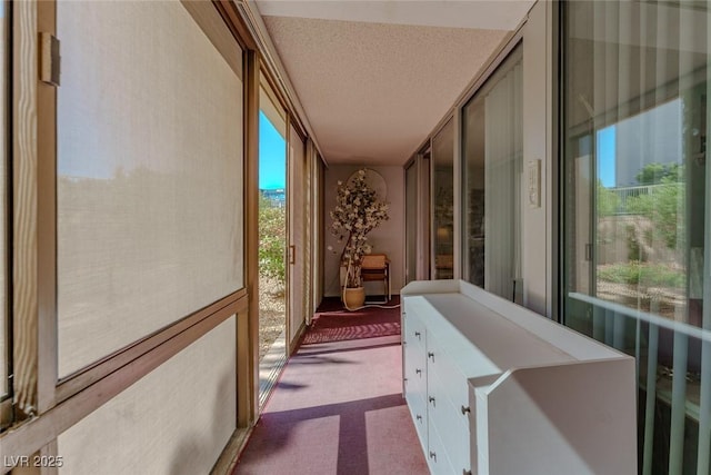 hallway featuring dark carpet and a textured ceiling