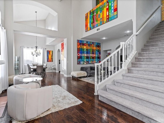 entryway with high vaulted ceiling, dark hardwood / wood-style floors, and an inviting chandelier