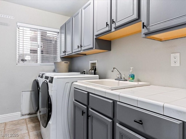 washroom featuring separate washer and dryer, sink, light tile patterned floors, and cabinets