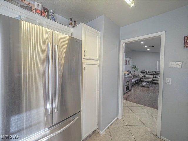 kitchen with white cabinetry, light tile patterned floors, and stainless steel fridge