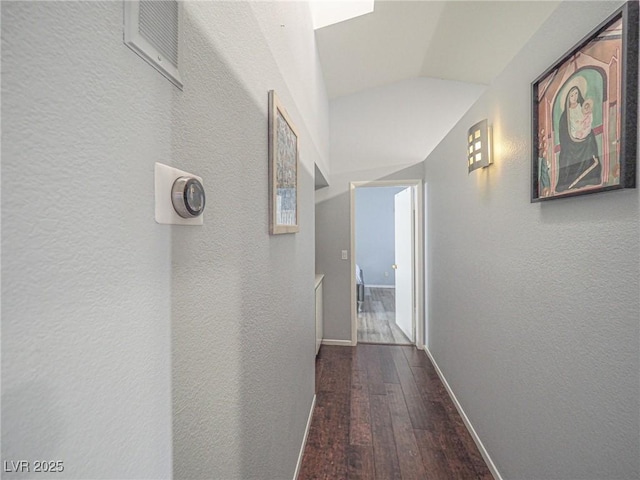 corridor with wood-type flooring and lofted ceiling