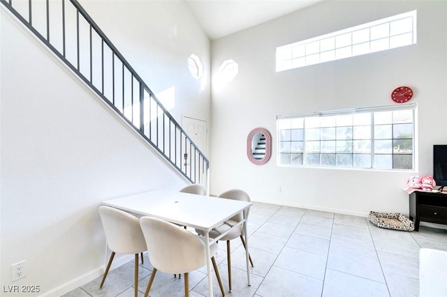 tiled dining space featuring a high ceiling and a wealth of natural light