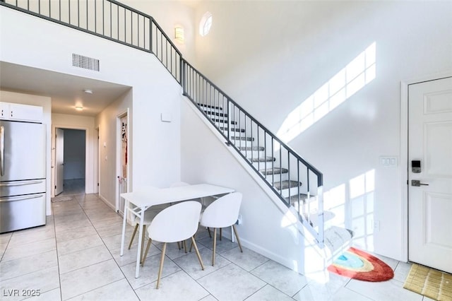 dining area featuring light tile patterned floors, a wealth of natural light, and a high ceiling