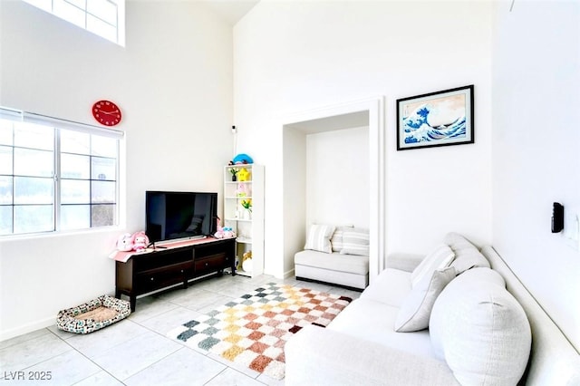 living room with plenty of natural light, a towering ceiling, and light tile patterned floors