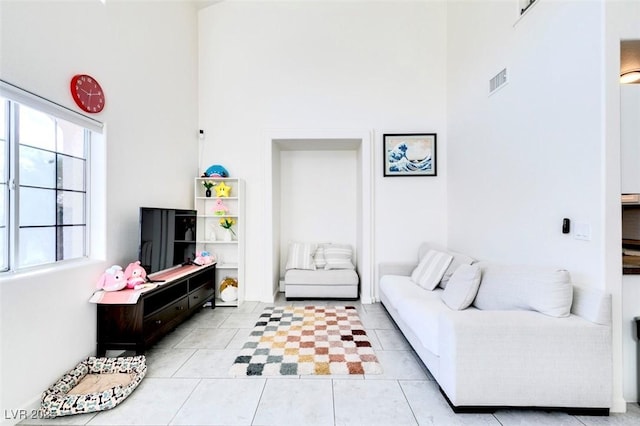 tiled living room featuring a towering ceiling